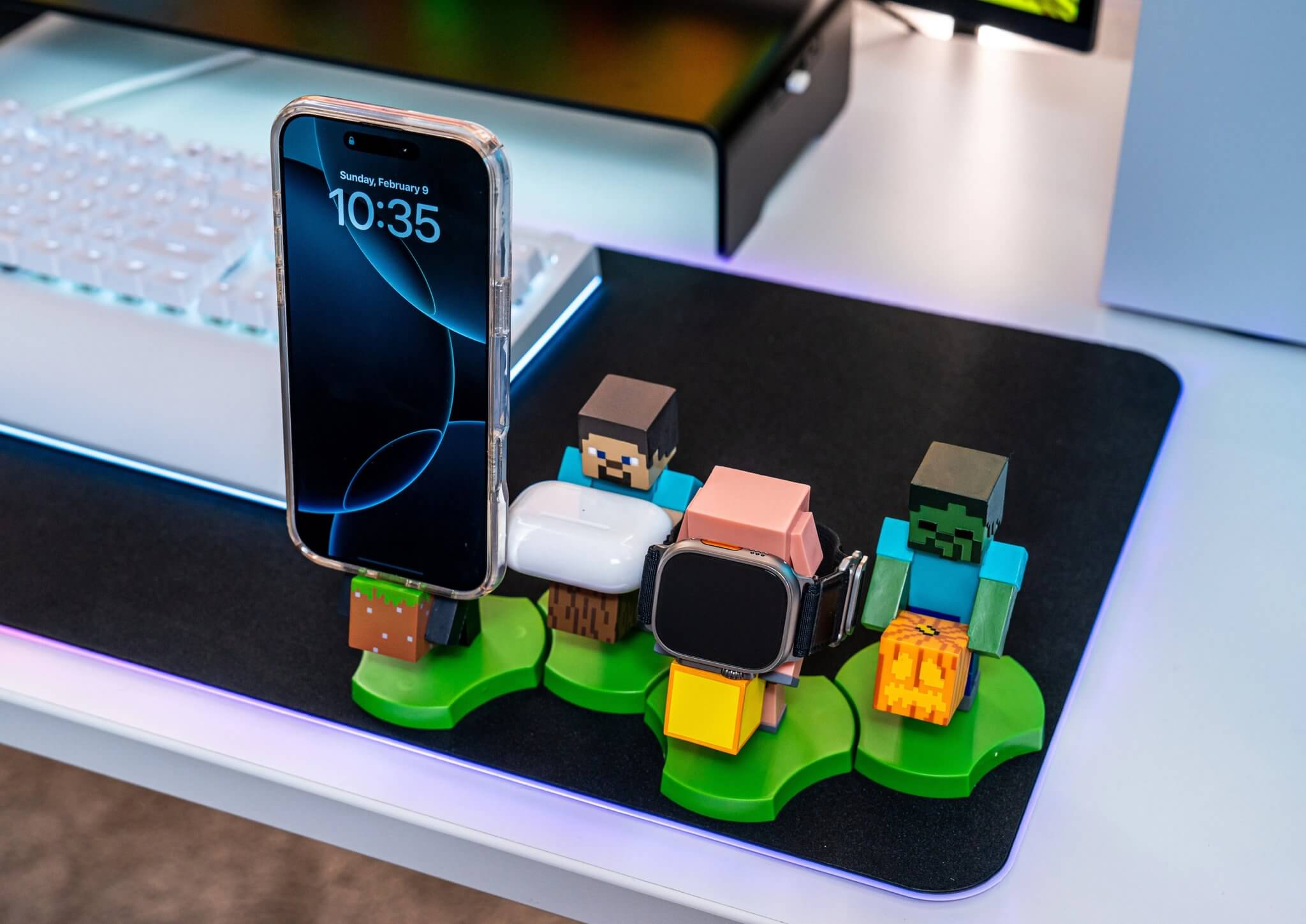 Phone, watch, and smartphone on a stand with colorful Minecraft figures on a desk.